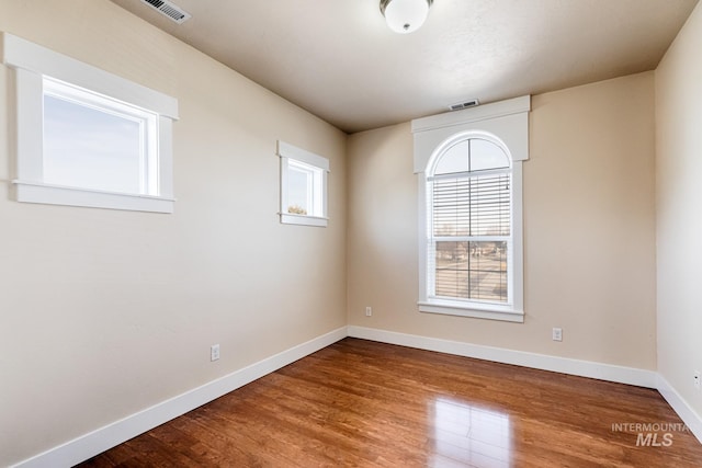 unfurnished room featuring visible vents, baseboards, and wood finished floors