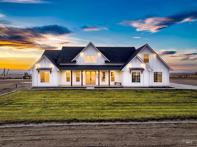 modern farmhouse style home with a porch and a lawn