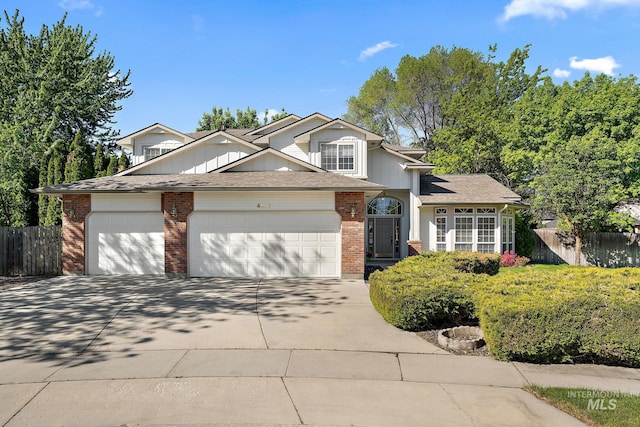traditional home featuring fence, concrete driveway, a garage, board and batten siding, and brick siding