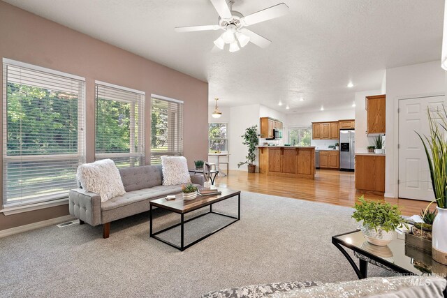 living area with a ceiling fan, a textured ceiling, baseboards, light colored carpet, and recessed lighting