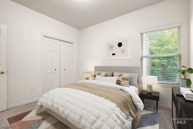 bedroom with carpet floors, baseboards, a textured ceiling, and a closet