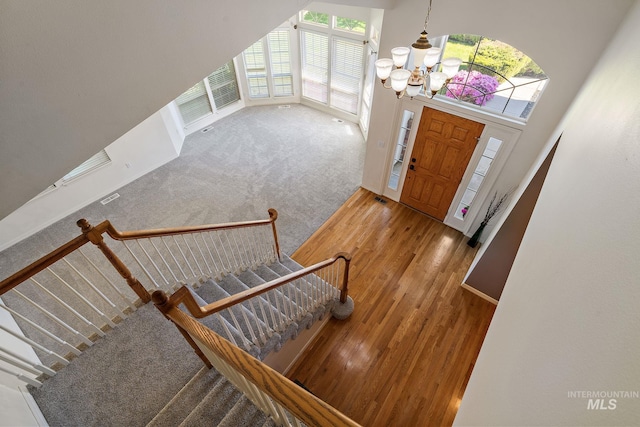 entrance foyer featuring a chandelier, stairs, wood finished floors, and carpet floors