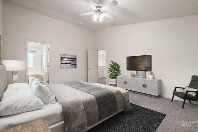 carpeted bedroom featuring vaulted ceiling, ensuite bath, and a ceiling fan