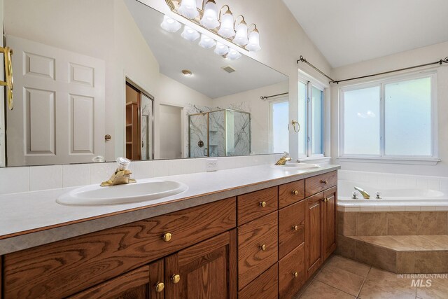 full bathroom featuring lofted ceiling, a stall shower, a bath, tile patterned floors, and double vanity