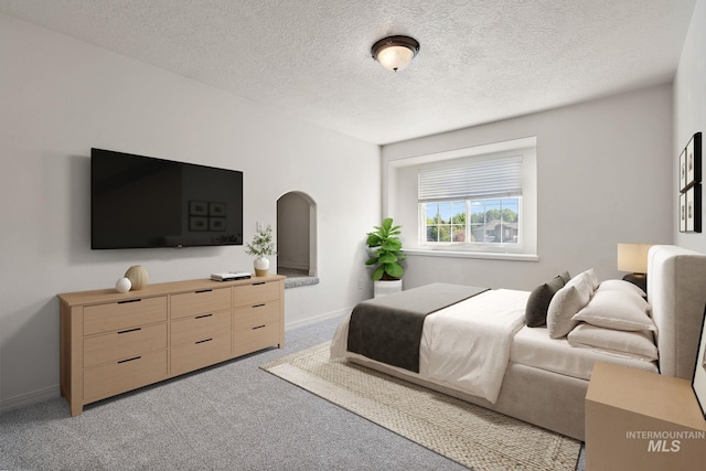 bedroom featuring light carpet, baseboards, and a textured ceiling