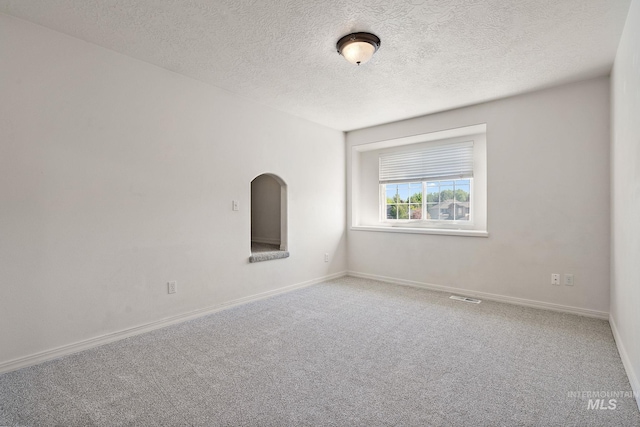 carpeted spare room with a textured ceiling and baseboards