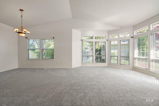 spare room with a chandelier, vaulted ceiling, plenty of natural light, carpet, and a textured ceiling