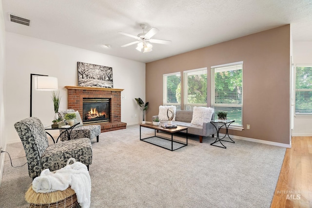 living room with healthy amount of natural light, a ceiling fan, a brick fireplace, and baseboards