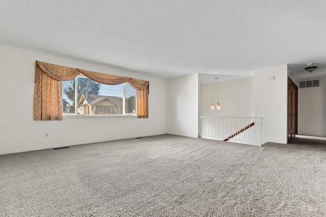 carpeted empty room featuring a textured ceiling