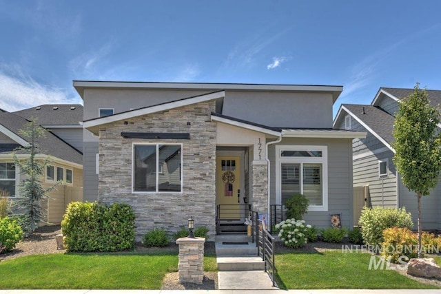 view of front of home featuring stone siding, a front yard, and stucco siding