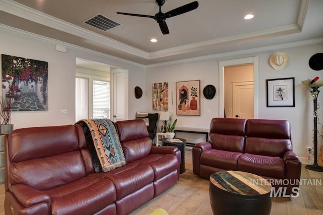 living area featuring visible vents, a tray ceiling, and crown molding