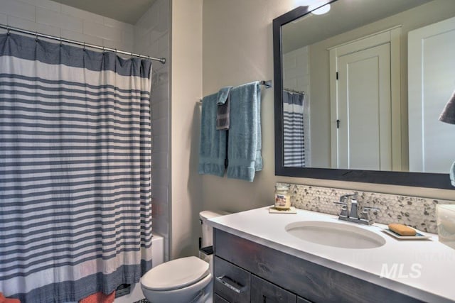 bathroom featuring toilet, shower / bath combo with shower curtain, and vanity