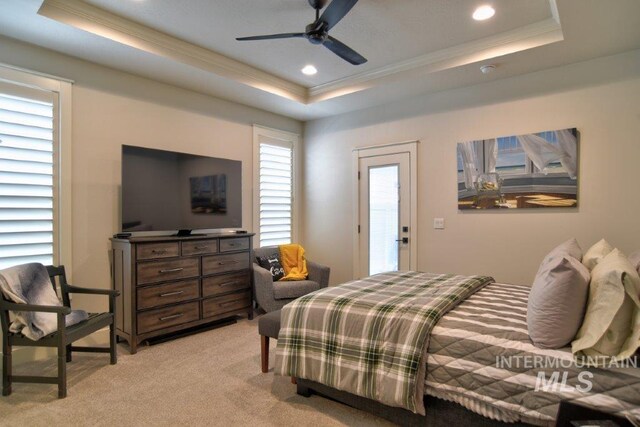 bedroom featuring ceiling fan, a raised ceiling, multiple windows, and light colored carpet