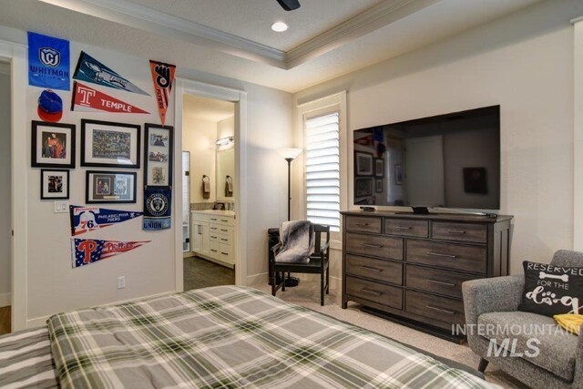 carpeted bedroom featuring ornamental molding, ensuite bathroom, and a raised ceiling