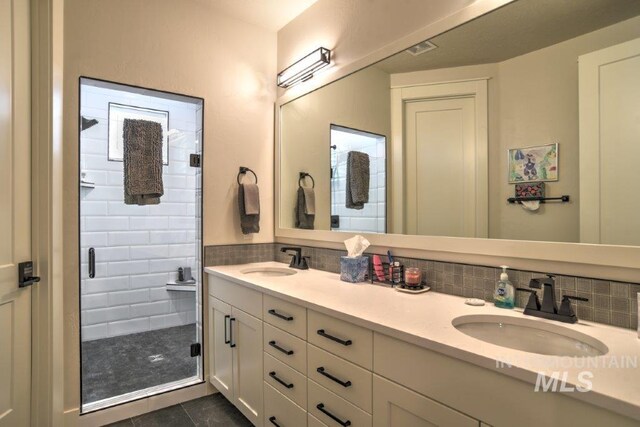 bathroom with double vanity, tasteful backsplash, walk in shower, and tile patterned floors