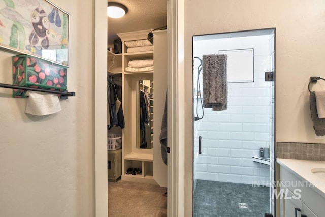 full bathroom featuring a stall shower, a spacious closet, and vanity