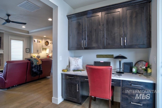 office featuring visible vents, a ceiling fan, ornamental molding, built in study area, and light wood finished floors