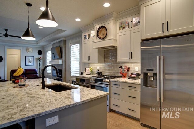 kitchen featuring stainless steel appliances, ornamental molding, sink, light wood-type flooring, and light stone countertops