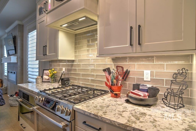 kitchen featuring backsplash, hardwood / wood-style flooring, light stone counters, and high end range