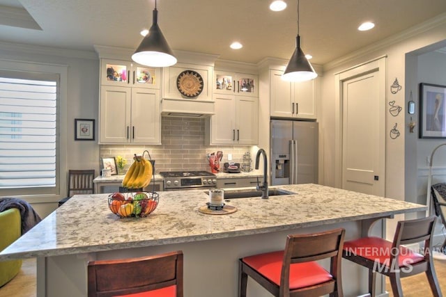 kitchen featuring crown molding, a breakfast bar area, backsplash, appliances with stainless steel finishes, and white cabinetry