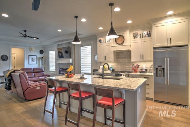 kitchen featuring stainless steel fridge, ornamental molding, open floor plan, a fireplace, and a sink