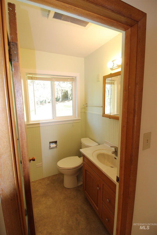 half bath with toilet, wainscoting, visible vents, and plenty of natural light