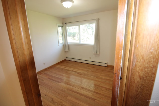 unfurnished room featuring light wood finished floors and baseboard heating