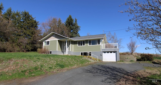 bi-level home with a front yard, an attached garage, and driveway