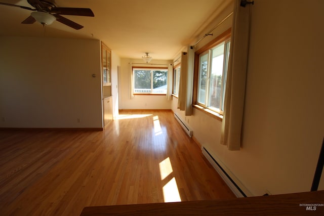 unfurnished room with ceiling fan, baseboard heating, baseboards, and wood finished floors