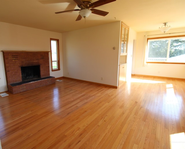 unfurnished living room featuring baseboards, light wood finished floors, a fireplace, and a ceiling fan