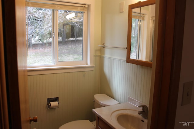 bathroom featuring toilet, vanity, and a wainscoted wall