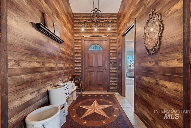 interior space with tile patterned floors, wooden walls, and a chandelier