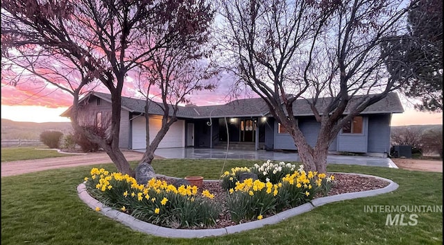 single story home with a lawn, cooling unit, and a garage