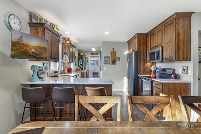 kitchen with a breakfast bar, sink, kitchen peninsula, and stainless steel appliances