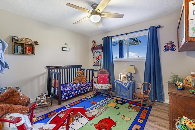 bedroom with ceiling fan, light hardwood / wood-style floors, and a textured ceiling