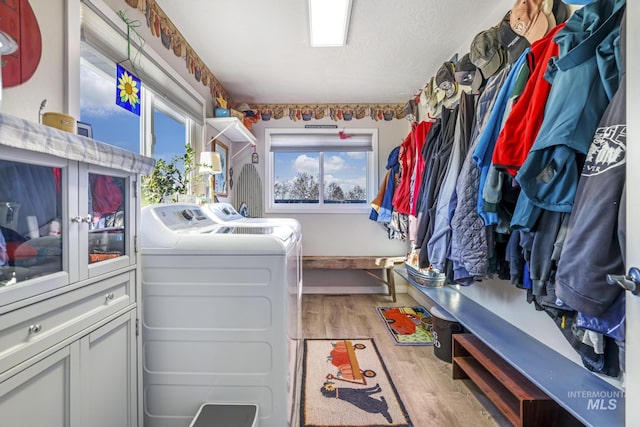 clothes washing area with washer and dryer and light wood-type flooring