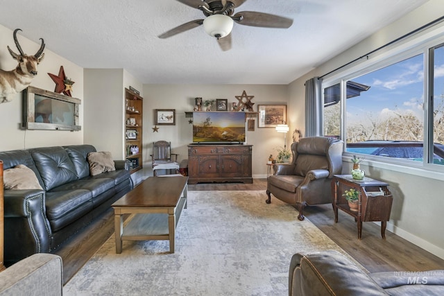 living room featuring ceiling fan, hardwood / wood-style floors, and a textured ceiling