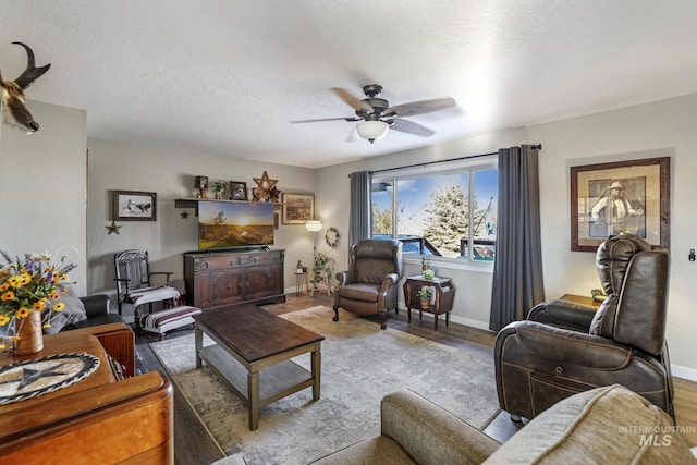 living room featuring ceiling fan, light hardwood / wood-style flooring, and a textured ceiling