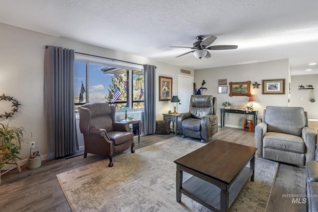living room featuring a textured ceiling, hardwood / wood-style flooring, and ceiling fan