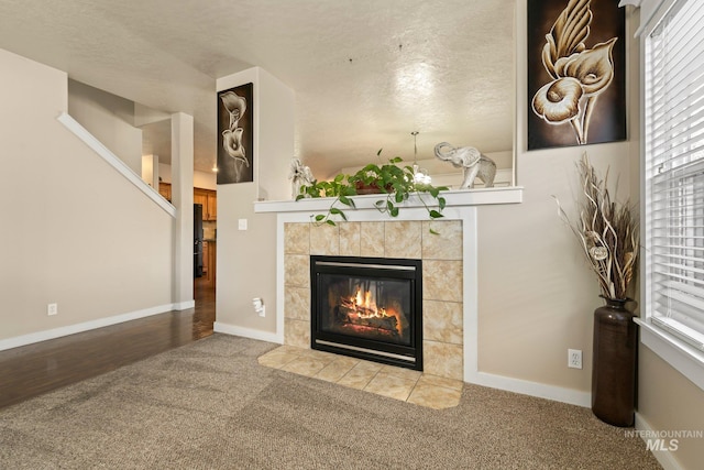 interior space with carpet, a tiled fireplace, and a textured ceiling