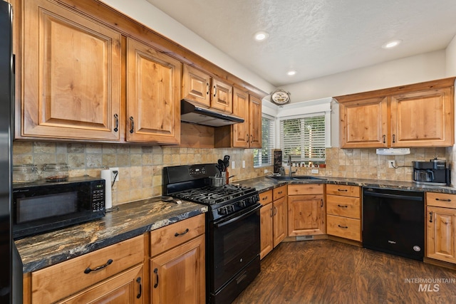 kitchen featuring black appliances, sink, backsplash, dark hardwood / wood-style flooring, and dark stone counters