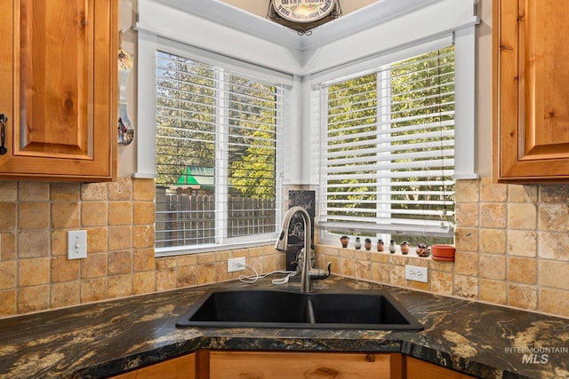 kitchen with decorative backsplash, dark stone countertops, and sink