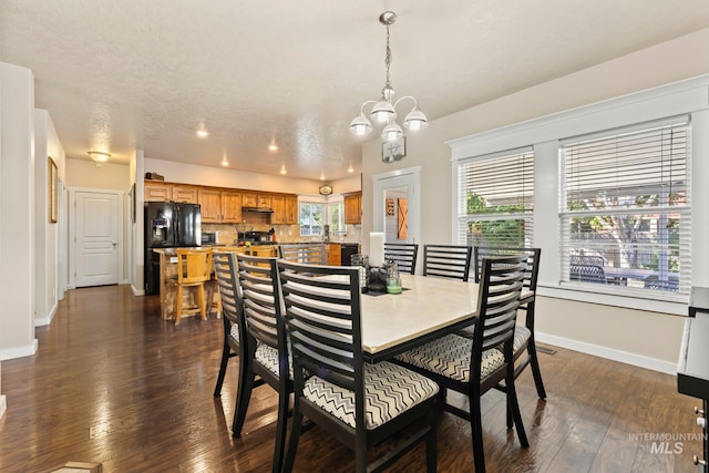 dining space with a notable chandelier, a textured ceiling, and dark hardwood / wood-style floors