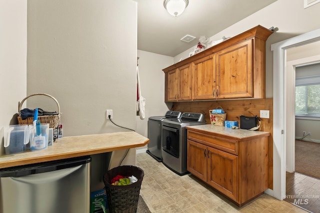 clothes washing area with cabinets and separate washer and dryer