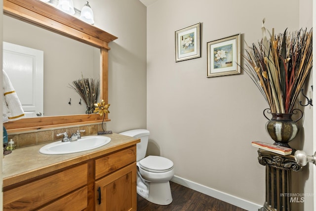 bathroom with toilet, hardwood / wood-style flooring, and vanity