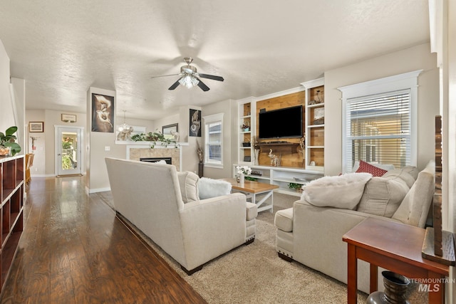 living room with a wealth of natural light, hardwood / wood-style floors, a tiled fireplace, and a textured ceiling