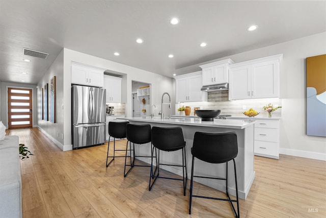 3067 N Sun City Ave, Star, ID 83669 - kitchen featuring freestanding refrigerator, light countertops, a kitchen island with sink, a breakfast bar, and backsplash