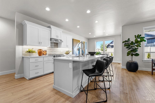 3067 N Sun City Ave, Star, ID 83669 - kitchen featuring a kitchen island with sink, healthy amount of natural light, backsplash, light wood finished floors, and recessed lighting