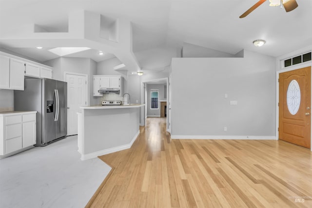 4104 Iris Ct, Nampa, ID 83687 - kitchen with stainless steel fridge, under cabinet range hood, vaulted ceiling, white cabinetry, and a ceiling fan