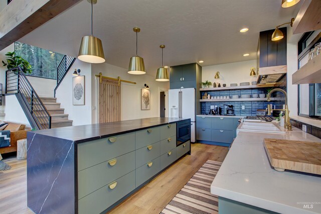 kitchen with light wood finished floors, open shelves, built in microwave, a sink, and a barn door